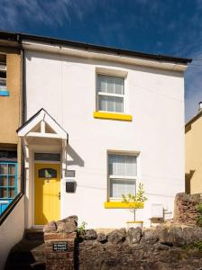 a white house with a yellow door and windows at *Brand New* Lemon Tree Cottage in Torquay