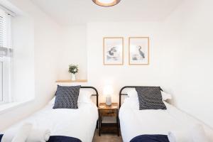 2 camas en una habitación con paredes blancas en *Brand New* Lemon Tree Cottage, en Torquay