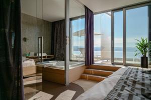 a bedroom with a bath tub and a bed and a window at Bevanda Hotel & Restaurant - Unique Adriatic in Opatija