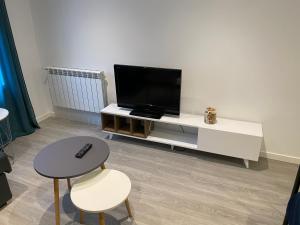 un salon avec une télévision sur un centre de divertissement blanc dans l'établissement Apartamento centro Santander B, à Santander