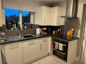 Stockton on the forestにある27 The Limes Room 1の白いキャビネットとコンロ付きオーブンを備えたキッチン