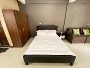 1 dormitorio con 1 cama grande y 1 sofá en Adam's Hotel Apartment en Pandi