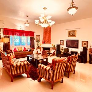 uma sala de estar com um sofá, uma mesa e cadeiras em Lakshmi Illam Guesthouse for Families only em Kodaikanal