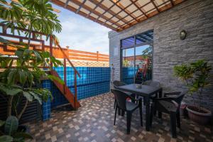 une terrasse avec une table, des chaises et une piscine dans l'établissement White Beach Holiday, à Hulhumalé