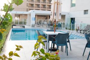 a patio with a table and chairs and an umbrella at Celi Connect Hotel Orla Aracaju in Aracaju