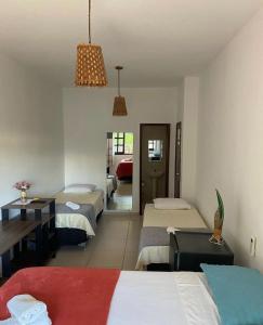 une chambre d'hôtel avec trois lits et une chambre avec un couloir dans l'établissement Pousada Pipas Gamboa, à Pipa