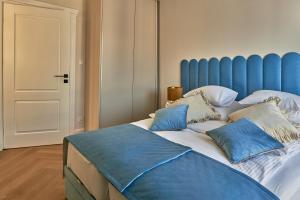 - un lit avec une tête de lit bleue et des oreillers dans l'établissement Apartament Primavera 3 MINI SPA Komfort dla grup biznesowych , rodzin ,osób indywidualnych, à Kielce