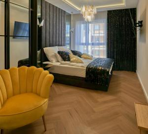 - une chambre avec un lit, une chaise et un lustre dans l'établissement Apartament Primavera 3 MINI SPA Komfort dla grup biznesowych , rodzin ,osób indywidualnych, à Kielce