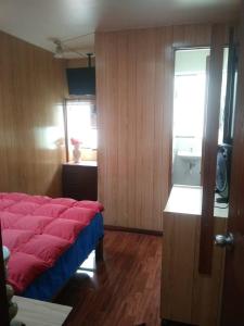 1 dormitorio con cama roja y ventana en Hospedaje Del Pilar en Magdalena del Mar, en Lima
