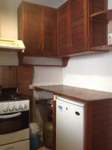 uma cozinha com uma geladeira branca e armários de madeira em Gloria em Piriápolis mais 4 fotografias