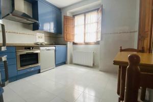 una cocina con armarios azules y una mesa. en apartamentos lleguera 1, en Llanes