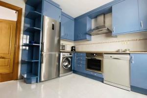 a kitchen with blue cabinets and a stainless steel refrigerator at apartamentos lleguera 1 in Llanes