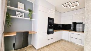 a kitchen with white cabinets and a black chair at Diamond Luxury Apartment in Budapest