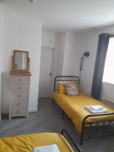 a bedroom with two beds and a dresser and a mirror at Flat 4 Corner House in Doncaster