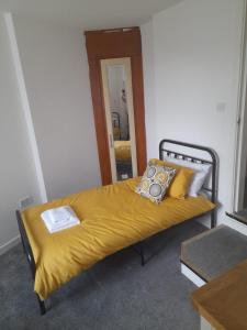 um quarto com uma cama com um cobertor amarelo em Flat 4 Corner House em Doncaster