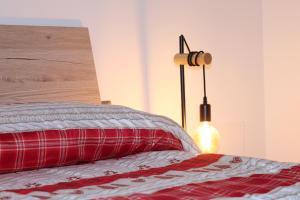 1 dormitorio con 1 cama con almohada roja y lámpara en IL CERVO - Dolomiti Affitti en Cavalese