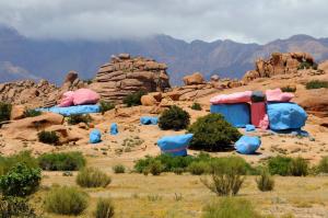 a group of structures in the desert with mountains at Azur Tafraout in Tafraoute