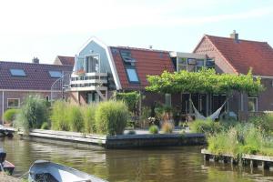a house on the side of a river with buildings at Vakantie Studio Grou in Grou