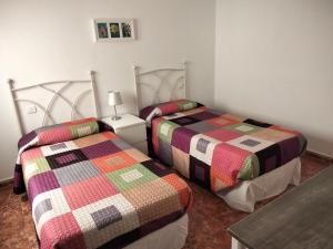 sypialnia z 2 łóżkami i kolorowymi kołdrami w obiekcie Casa candelaria w mieście Arinaga