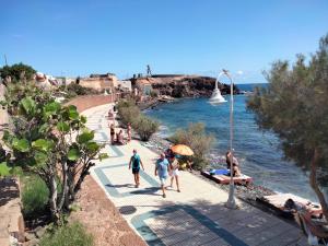 grupa ludzi chodzących po chodniku obok wody w obiekcie Casa candelaria w mieście Arinaga