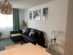 a living room with a black couch and a table at Superbe appartement neuf T3 de 71m2 en résidence a Marseille in Marseille