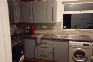 a kitchen with a sink and a washing machine at Cheerful 3 Bedroom Apartment in Nottingham