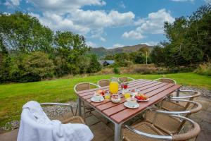 a wooden table with food and orange juice on it at Wildwood Cottage with Hot Tub in Glencoe