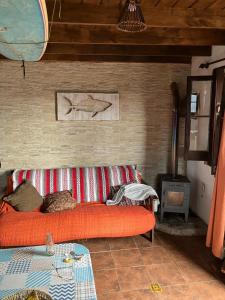 a living room with a red couch and a fish picture on the wall at Abuelo Andrés in Punta Del Diablo +38 photos