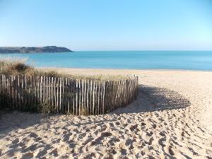 a wooden fence on a sandy beach with the ocean at Les coquetières in Roz-sur-Couesnon