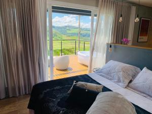 a bedroom with a bed and a balcony with a tub at Vista Vigneti Albergo & Vino - Vale dos Vinhedos in Bento Gonçalves