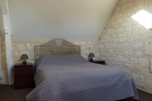 a bedroom with a bed and a stone wall at Gîte des Basses Rivières in Huismes