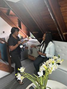 two women standing in a room with a bottle of wine at Private 2 Bedroom Beachfront Penthouse Condo Ocho Rios, Jamaica in Ocho Rios