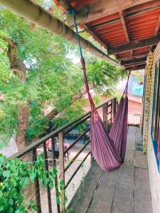 a purple hammock hanging from a porch with trees at SAMO Hostel in Pipa