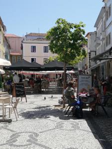 Un hombre sentado en una mesa bajo una sombrilla en una calle. en Aveiro Soul & Heart apartment, en Aveiro