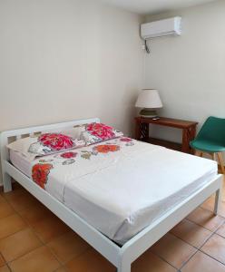 ポワンタピートルにあるAppt Morne la Logeのベッドルーム1室(赤い花の白いベッド1台付)