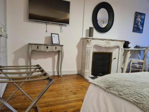 - une chambre avec une télévision, une chaise et une cheminée dans l'établissement Le Relais de l'endormie, à Nogent-sur-Seine