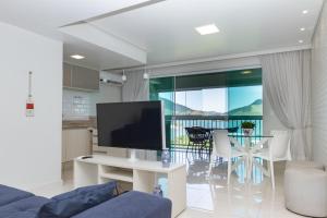 a living room with a television and a table with chairs at Requinte à beira mar! Recarregue suas energias! in Angra dos Reis