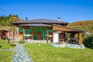 a house with a garden and a patio at Holiday Home Green in Rakovica