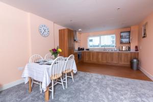 a dining room with a table and chairs and a clock at Meridian Bay Apartment in Swansea