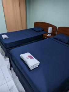 two beds with blue sheets and a white towel at Cuartos Casa Blanca in León