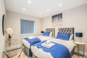 1 Schlafzimmer mit 2 Betten mit blauer und weißer Bettwäsche in der Unterkunft Langston House: 2 Bed, 2 Bath Luxury Apartment in Hedgerley