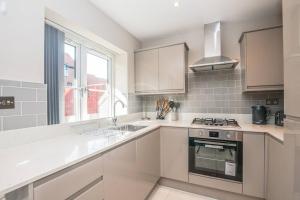 cocina blanca con fogones y fregadero en Langston House: 2 Bed, 2 Bath Luxury Apartment en Hedgerley