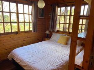 a bedroom with a bed with white sheets and windows at La Cabaña de Heidi in Concordia