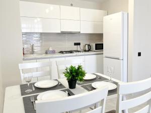 a white kitchen with a dining table and white cabinets at OASIS, Charming 1BD apartment with living room in Chişinău
