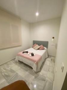 um quarto com uma cama com lençóis cor-de-rosa e almofadas cor-de-rosa em C Ciruelo 7 em Lora del Río