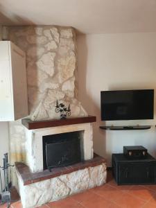 a living room with a stone fireplace with a flat screen tv at La Casetta di Margi in Ateleta