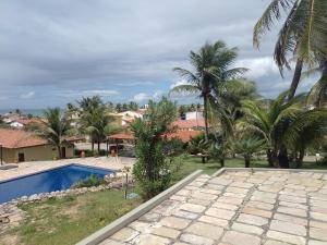 a resort with a swimming pool and palm trees at Condomínio Mar de Búzios in Nísia Floresta