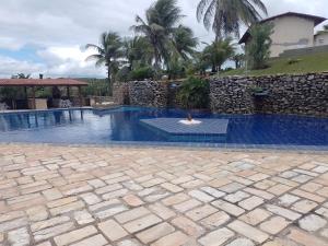 a swimming pool in a yard with a stone wall at Condomínio Mar de Búzios in Nísia Floresta