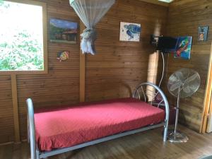 1 dormitorio con cama roja en una pared de madera en Chalet en bois, en Saint-Claude