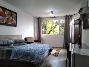 a bedroom with a bed and a large window at Pousada Casa Verde - Curitiba in Curitiba